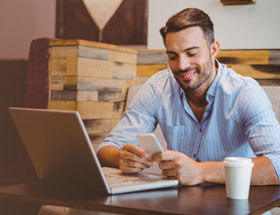 handsome man updating his online dating profile in a cafe