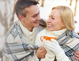 Happy couple snuggling under a blanket