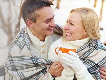 Happy couple snuggling under a blanket