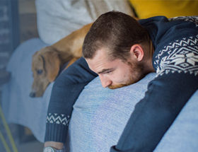 Emotional man on bed with sad dog