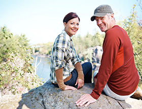 Couple sitting on a rock enjoying a nice view of a forest