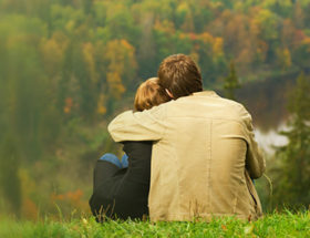 couple facing away hugging on the grass