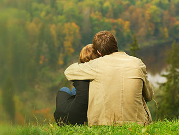 couple facing away hugging on the grass