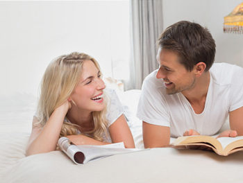 Happy couple reading on the bed together, demonstrating their happy, monogamous relationship