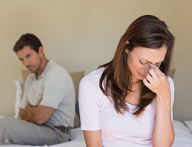 Couple sitting on bed confronting the fact that one of them has cheated