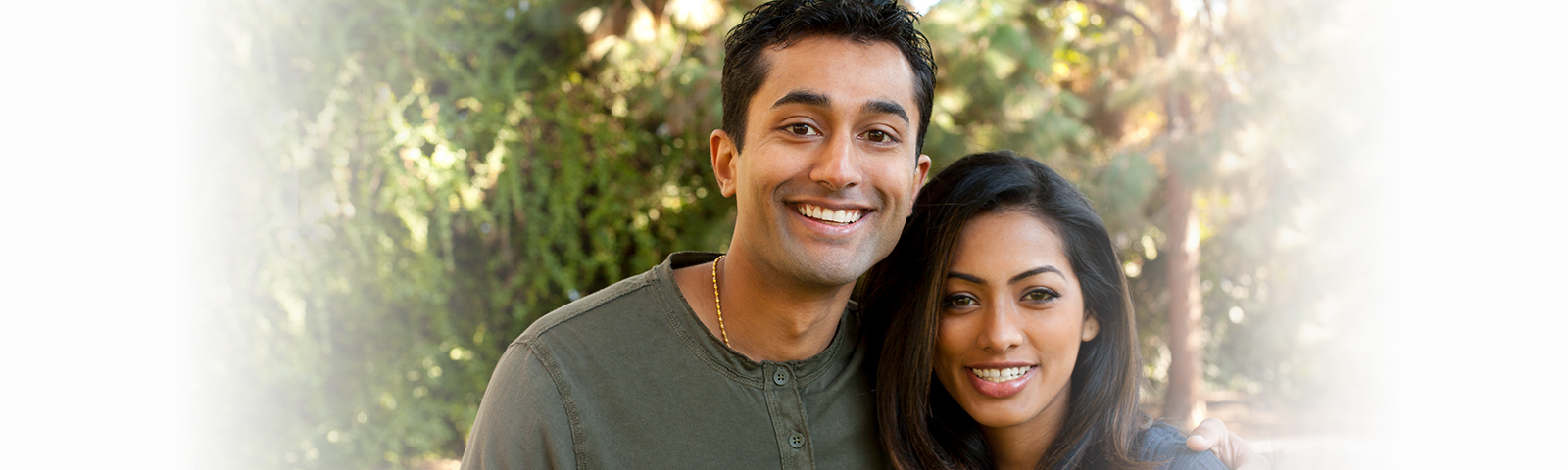 Indian dating couple smiling by a tree