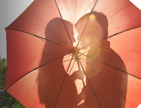 Couple about to kiss behind an umbrella