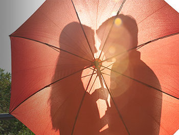 Couple about to kiss behind an umbrella