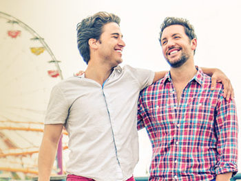 Two men walking arm in arm along a pier